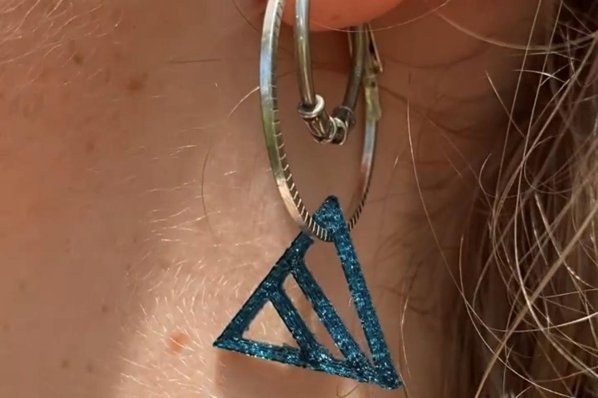 Blå trekantet ørepynt i et øre 